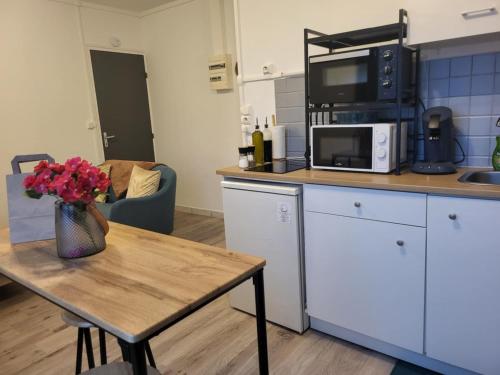 une cuisine avec une table avec un vase de fleurs dessus dans l'établissement Le Fassio - Wifi - Stationnement gratuit, à Lens