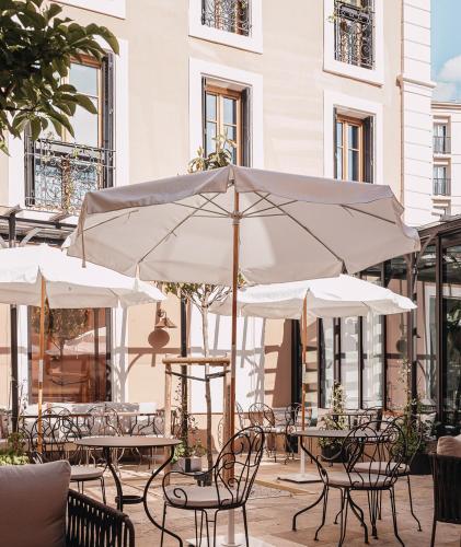 a patio with tables and chairs with umbrellas at Grand Hôtel Du Parc - Teritoria in Aix-les-Bains