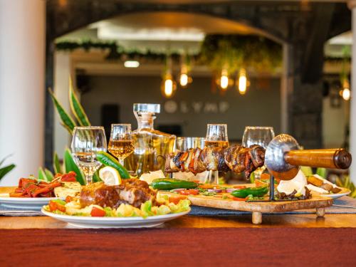 a table with plates of food and glasses of wine at SPA Hotel Olymp in Velingrad