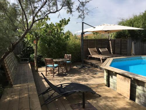 une terrasse avec une piscine, une table et un parasol dans l'établissement Belle villa 3km de la mer, à Marseillan