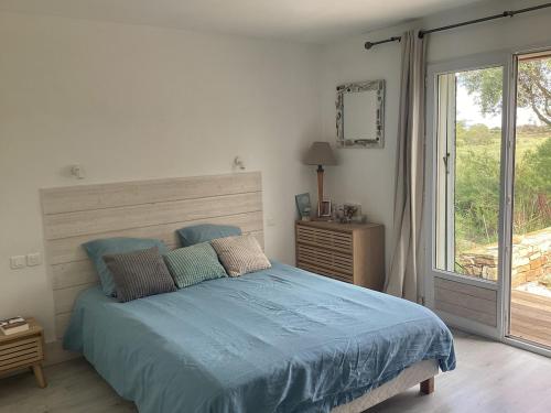 une chambre avec un lit avec des draps bleus et une fenêtre dans l'établissement Belle villa 3km de la mer, à Marseillan