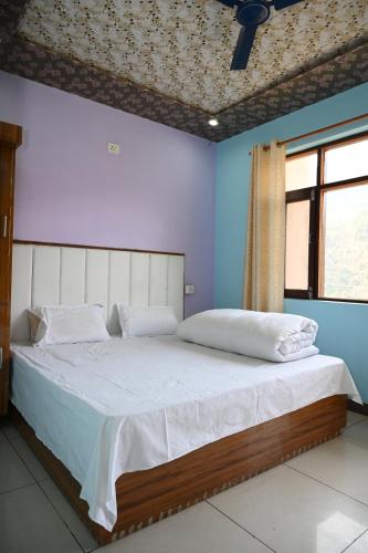 a bedroom with a large bed with blue walls and a window at RK Residency Ukhimath in Ukhimath