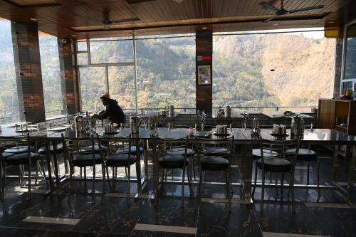 a person sitting at a table in a restaurant with a view at RK Residency Ukhimath in Ukhimath