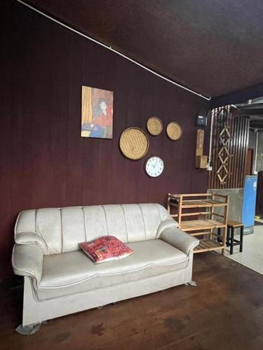 a living room with a white couch and clocks on the wall at Thai Wooden Garden House By Paddy Fields Haven - Natures Nest in Pai