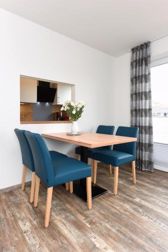 a dining room with a wooden table and blue chairs at Zur Möwe 1 in Esens