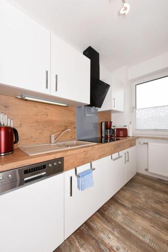 a kitchen with white cabinets and a sink at Zur Möwe 1 in Esens