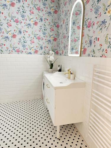 La salle de bains est pourvue d'un lavabo blanc et de papier peint à fleurs. dans l'établissement Art&Heart - Centre historique, idéal Feria de Béziers, à Béziers