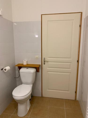a bathroom with a white toilet and a door at gîtes "Entre les Vignes" in Tourreilles