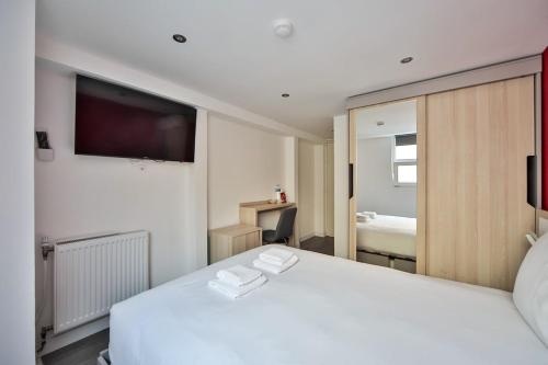 une chambre avec un lit blanc et une télévision dans l'établissement 09 Studio Charenton Fitness Cinema, à Charenton-le-Pont