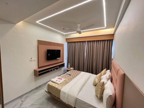 a bedroom with a bed and a flat screen tv at Hotel Melbourne in Gandhinagar