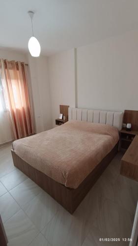 ein Schlafzimmer mit einem großen Bett und einem Fenster in der Unterkunft ILSA Apartment in Durrës