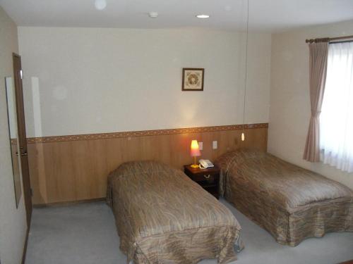 a hotel room with two beds and a window at Gasthof Ascot in Hokuto