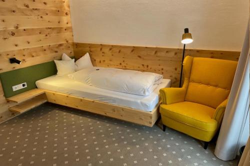 a bedroom with a bed and a yellow chair at Gästehaus Sonnenheim in Mittenwald