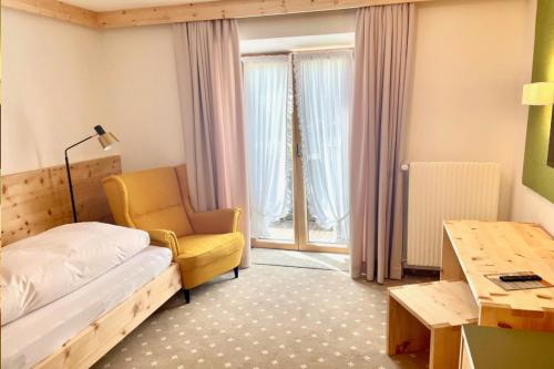 a bedroom with a bed and a chair and a desk at Gästehaus Sonnenheim in Mittenwald