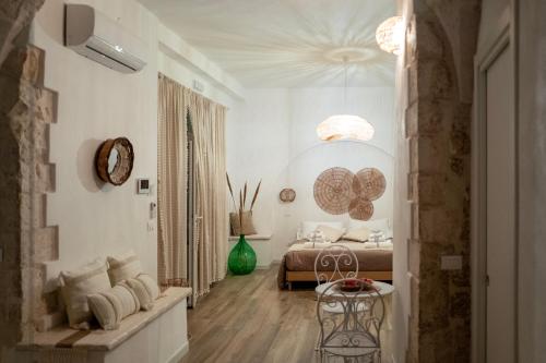 a white bedroom with a bed and a table at Dimore Piazza Vecchia Wellness Suites in Castellana Grotte
