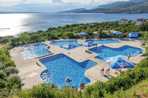 an overhead view of two pools with umbrellas and the ocean at Camping Klenovica in Klenovica