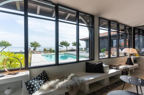 - un salon avec des fenêtres donnant sur la piscine dans l'établissement Demeure d'exception vue mer, à Andernos-les-Bains