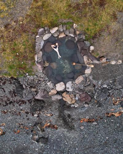 a man is standing in a small pool of water at Hvammsvík Nature Resort in Kjósahreppur