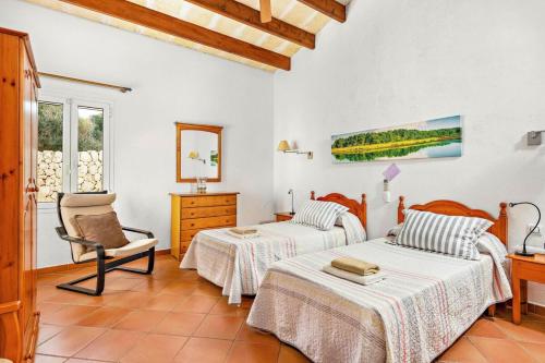 a bedroom with two beds and a chair in it at Finca Llucasaldent Menor by Menorca Vacations in Alaior