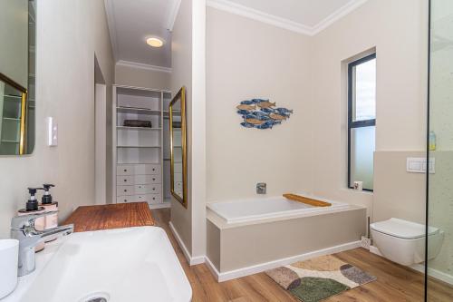 a bathroom with a tub and a toilet and a sink at Lighthouse Villa Romansbaai in Gansbaai
