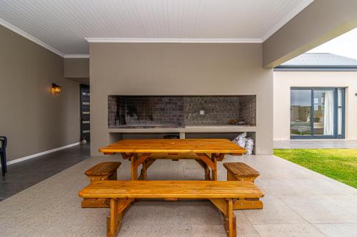 a patio with a wooden table and benches at Lighthouse Villa Romansbaai in Gansbaai