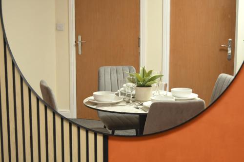 a dining room with a table and chairs and a mirror at Warrington Suites by Relax Stays in Warrington