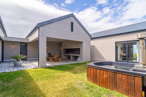 a white house with a backyard with a hot tub at Lighthouse Villa Romansbaai in Gansbaai