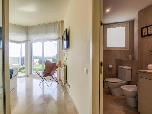 baño con aseo, silla y ventana en Luxury Seaview Apartment by Hello Homes Sitges, en Sitges