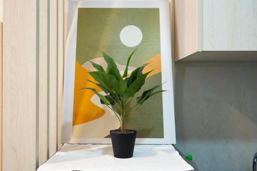 a plant sitting on a shelf in front of a picture at Otis Soho Saigon Balcony Apartment in Ho Chi Minh City