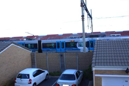 a blue train traveling over a house with cars at South Peninsula Beach Apartment in Cape Town