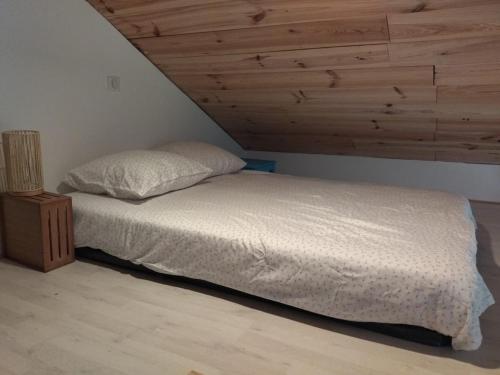 Ce lit se trouve dans une chambre dotée d'un plafond en bois. dans l'établissement Cabane et jardinet, à Magescq