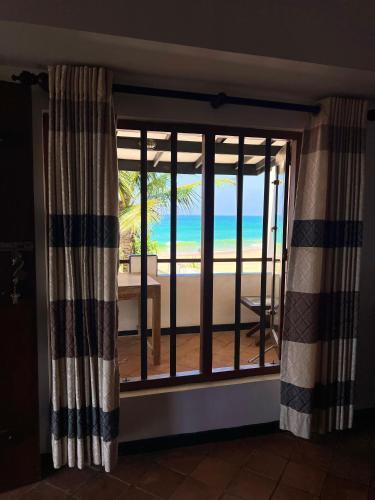 a room with a window with a view of the beach at Sailors' Bay in Hikkaduwa