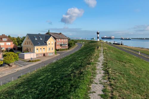 a grassy hill next to a road and houses at Moderne Fewo "Feuerwache" direkt am Elbdeich bei Moldenhauer in Twielenfleth