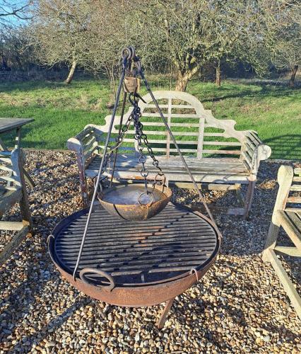 a metal swing in front of a park bench at Low Farm Barn, a family and dog friendly haven in Brundish