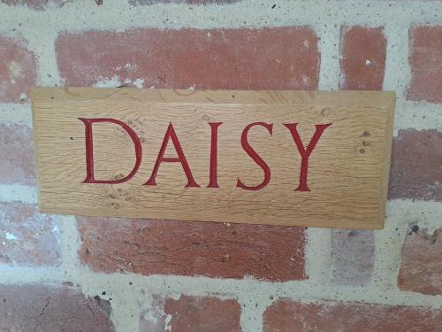 a wooden sign with the wordiasis hanging on a brick wall at Low Farm Barn, a family and dog friendly haven in Brundish