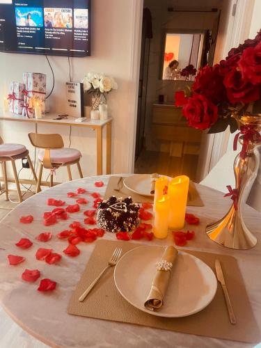 a table with two plates and red roses on it at Delightful little house & Chateau Charme Suite in Auckland