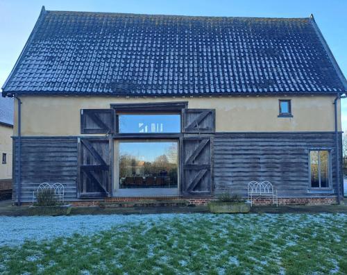 a house with a large window on the side of it at Low Farm Barn, a family and dog friendly haven in Brundish
