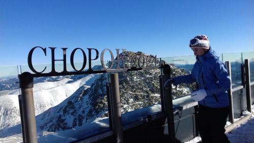 a person standing next to a sign at the top of a mountain at Apartmán Margarétka in Liptovský Trnovec