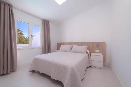 a white bedroom with a bed and a window at Villa Nina Lanzarote in Puerto del Carmen
