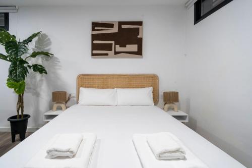 Un dormitorio con una cama con sábanas blancas y una planta en VLC Host - Tamarit, en Valencia