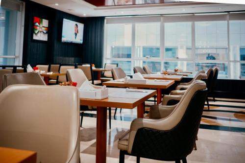 a dining room with tables and chairs and windows at Al Diar Sawa Hotel Apartments in Abu Dhabi
