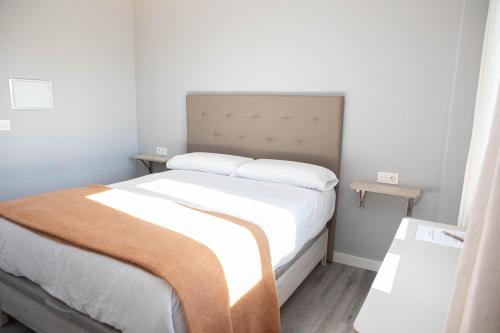 a bedroom with a large bed with white sheets at Hostal Rosario Galindo in Cúllar-Vega