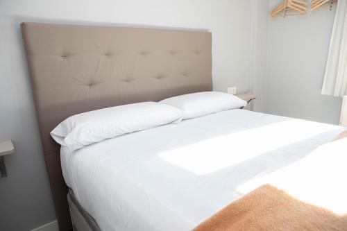 a white bed with two pillows on top of it at Hostal Rosario Galindo in Cúllar-Vega