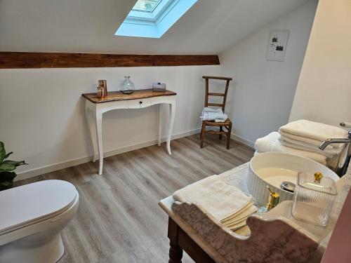 a bathroom with a toilet and a sink and a table at Les chambres de Luciole in Asnières-lès-Dijon