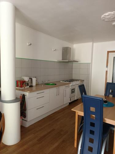 une cuisine avec des placards blancs, une table et des chaises bleues dans l'établissement Appartement avec terrasse a deux pas des thermes, à Bourbon-lʼArchambault