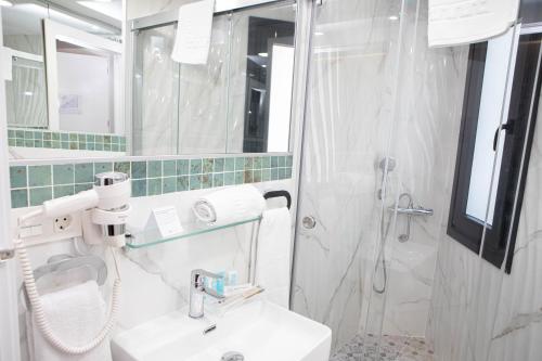 a white bathroom with a sink and a shower at Hostal Rosario Galindo in Cúllar-Vega