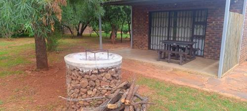 a fire pit next to a building with a picnic table at Kareespruit Game Ranch & Guest House in Zeerust