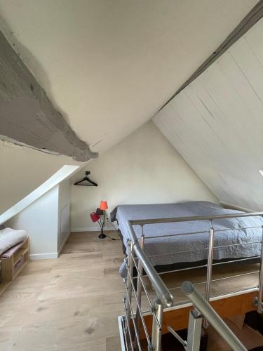 Cette chambre mansardée comprend un lit. dans l'établissement Charmant studio indépendant, à Oinville-sur-Montcient