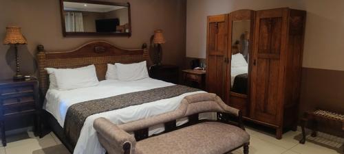a bedroom with a large bed and a mirror at Kareespruit Game Ranch & Guest House in Zeerust