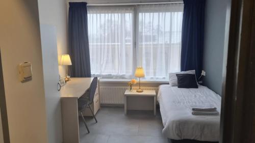a bedroom with a bed and a desk and a window at City Hotel Winschoten in Winschoten
